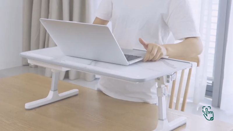 A portable foldable laptop table on a couch, showcasing easy storage and mobility options @ pickoutright.com